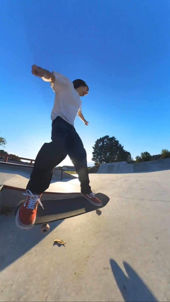 Young skater performing a trick at Macon Sense skatepark under clear blue skies.