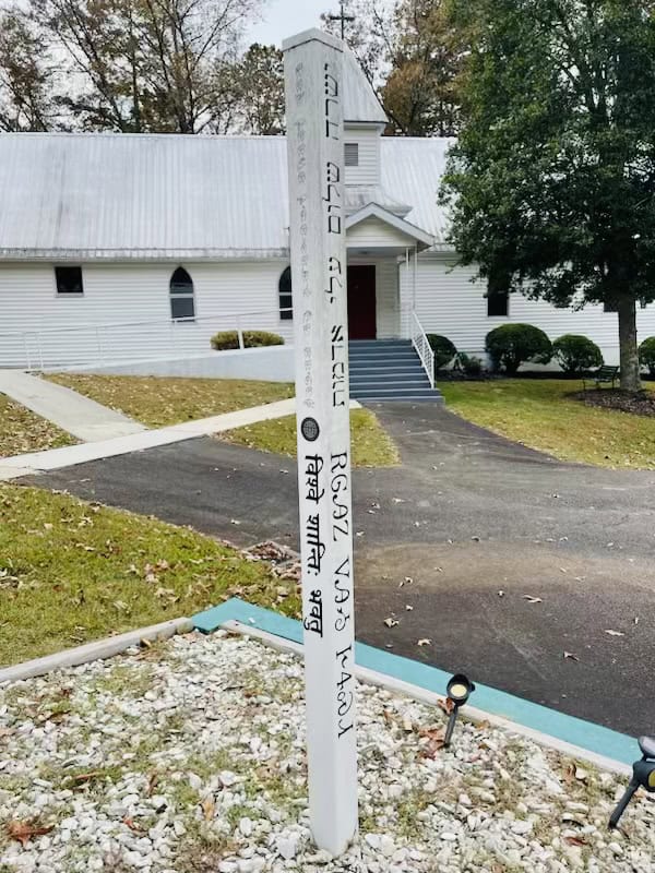 Community signpost at Macon church with religious inscriptions.