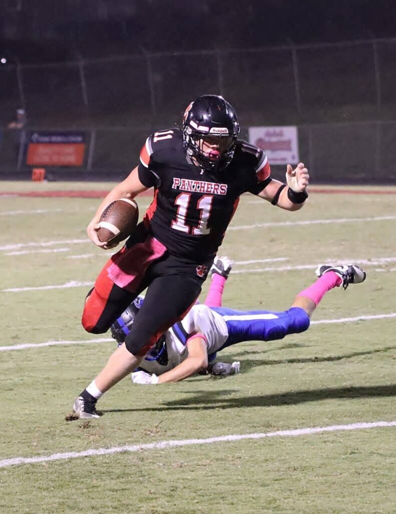 Football player running with ball during a game at night.