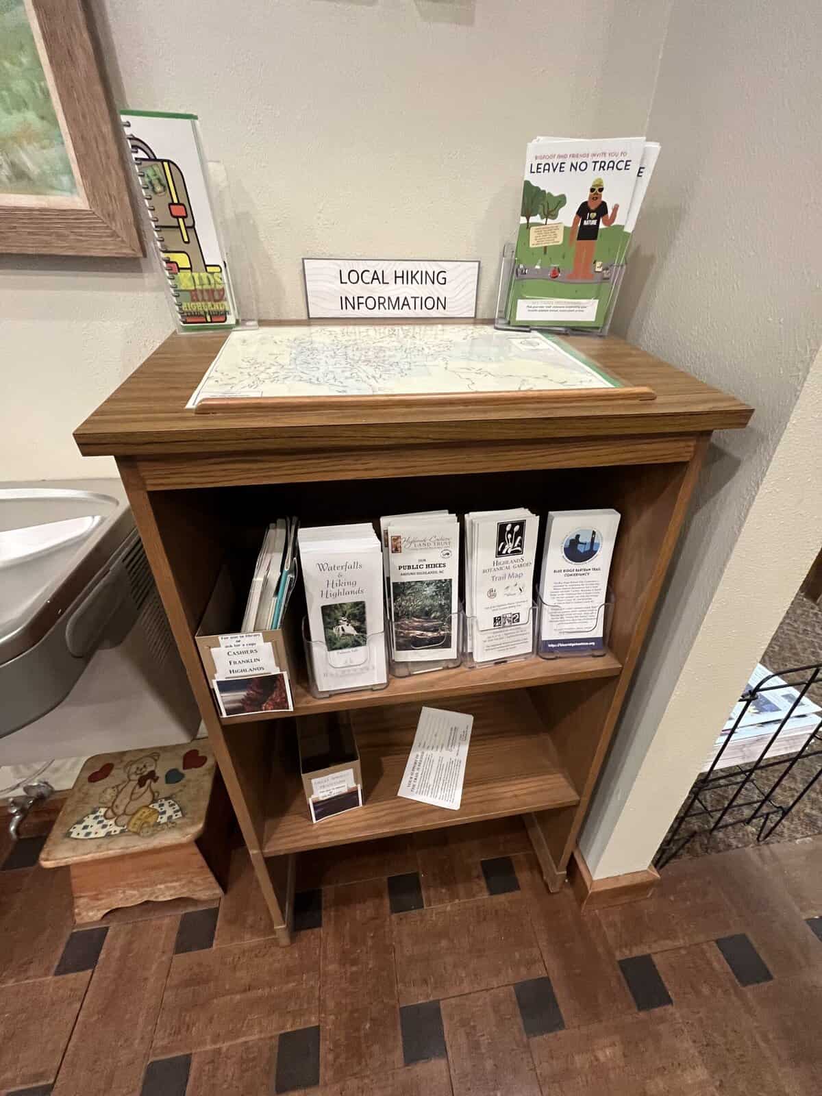 Wooden shelf with hiking maps and local guides for outdoor activities.