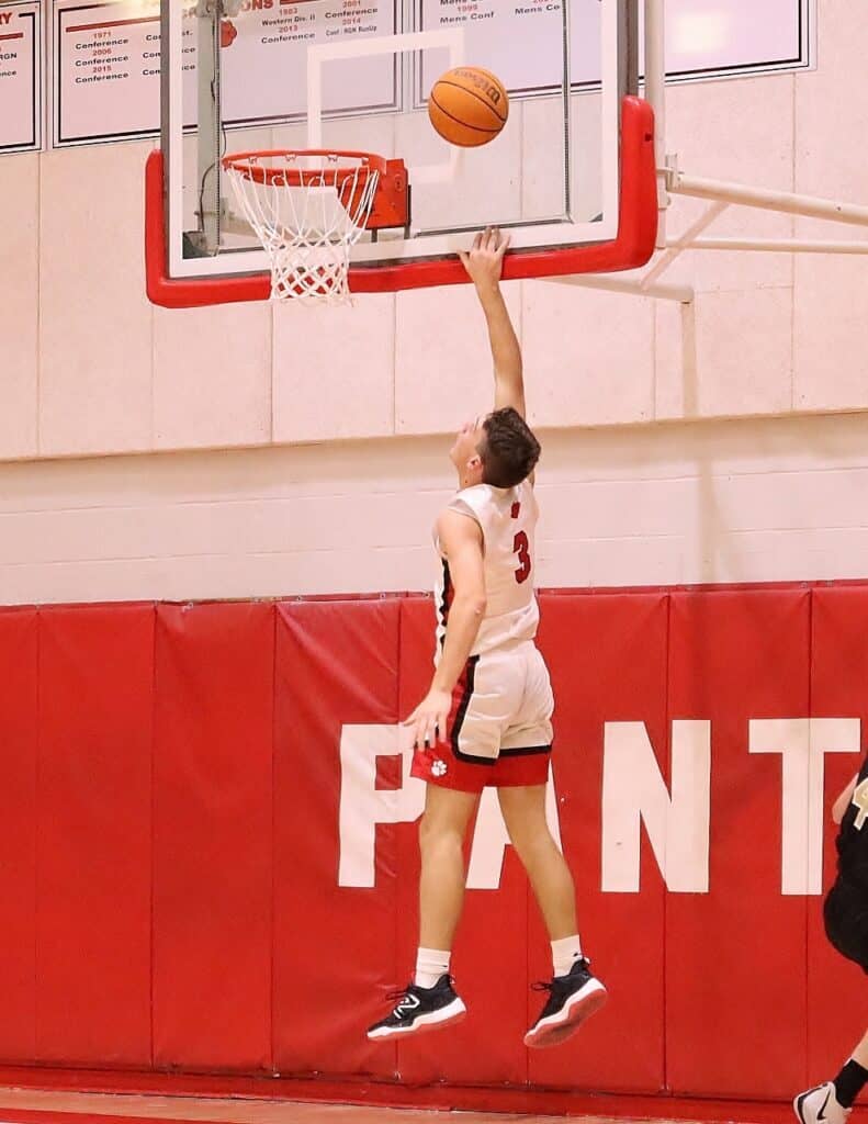 Young basketball player jumping to score a basket during a game.