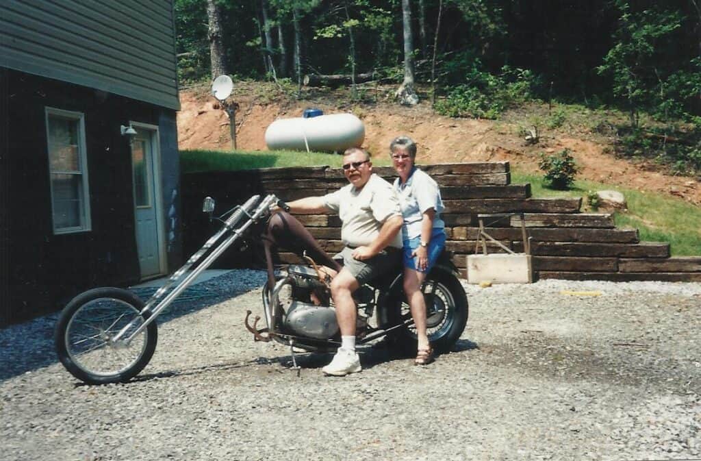 Couple with a motorcycle outdoors in Macon County, celebrating love.
