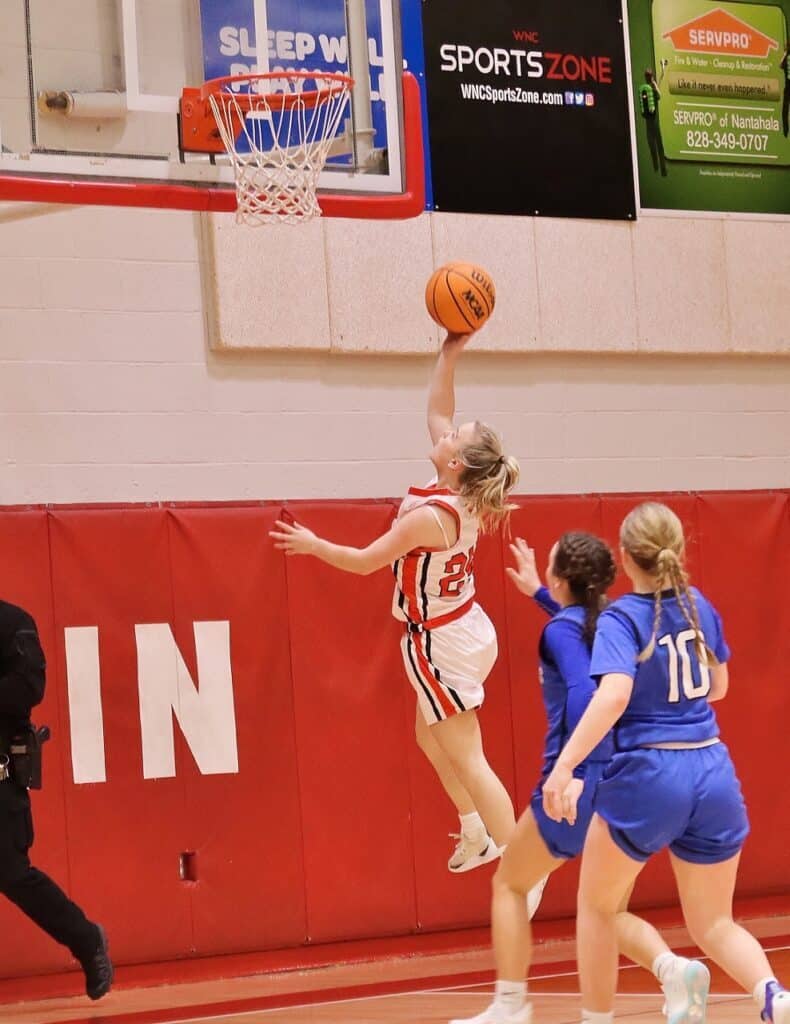 Junior varsity girls basketball player scoring a layup during a game.