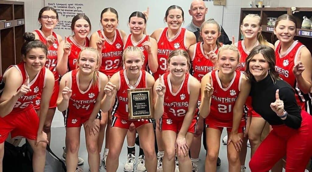 Young female basketball players celebrating victory with coach and trophy, winter sports success at.