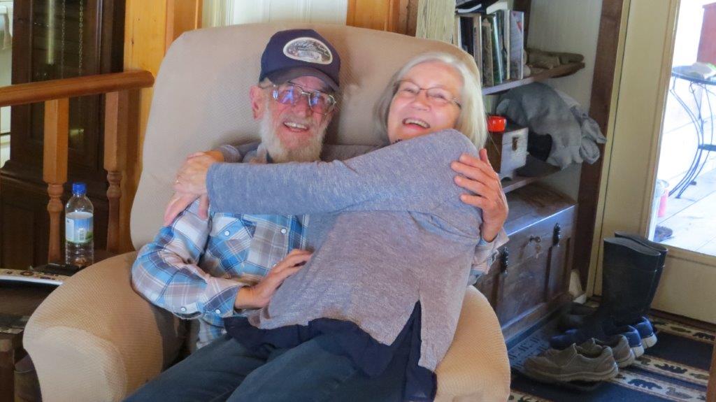 Happy elderly couple embracing on a cozy sofa in a warm home setting.