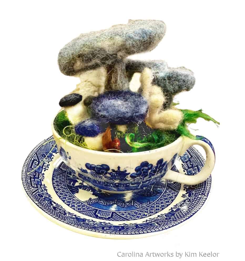 Wool art sculpture in a teacup, created by Kim Keelor, featuring colorful felted wool shapes.
