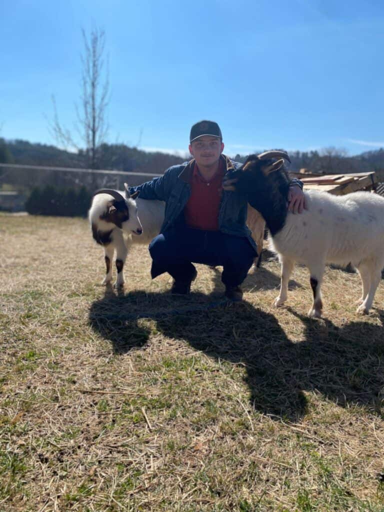 Student with goats at Bartram Academy farm visit, educational experience.