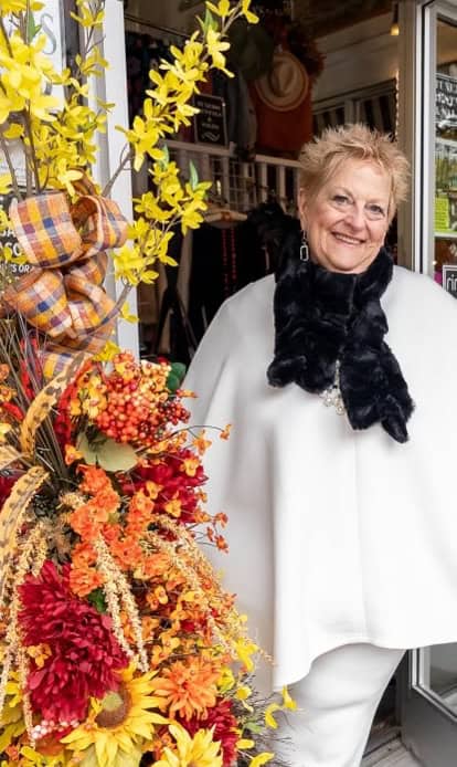 Elegant woman smiling near fall floral display.