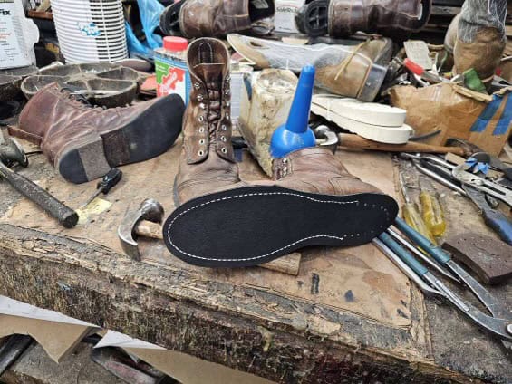 Shoe repair tools and boots in a workshop setting.