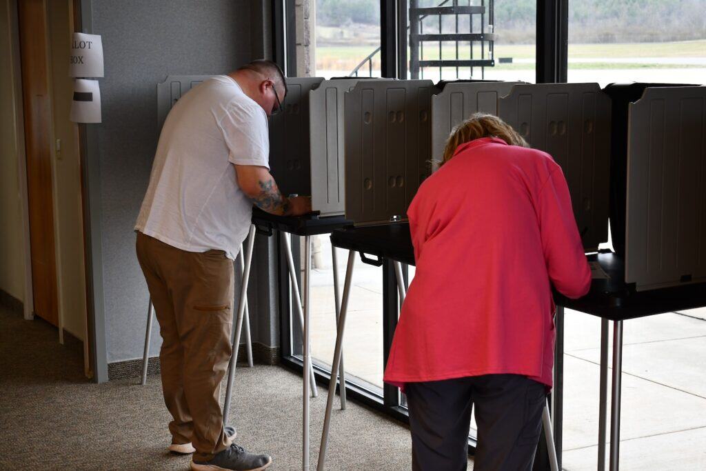 Two voters casting ballots at polling station during primary election.