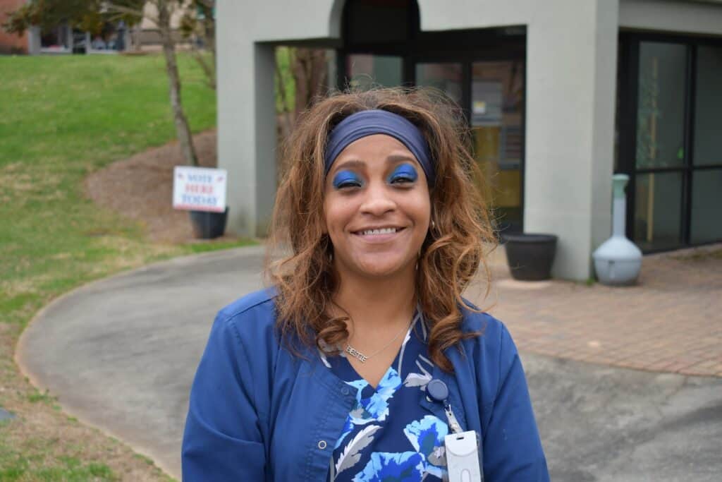 Woman smiling outside government building during election day.