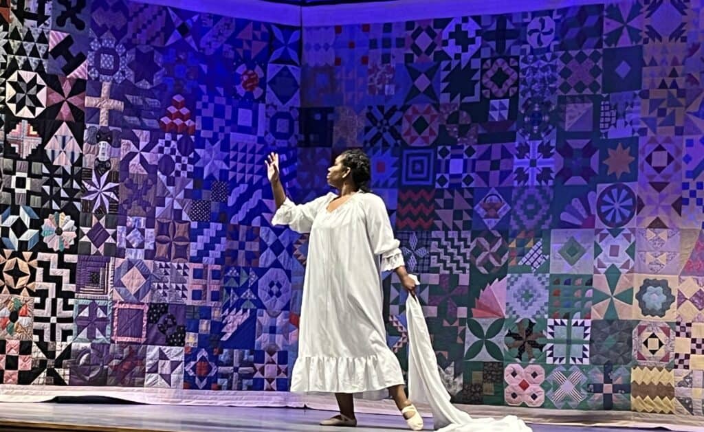 Woman unveiling a quilted mural honoring women of Macon County.