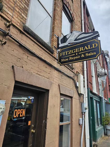 Shoe repair shop sign with a large sneaker graphic for Fitzgerald Shoe Repair & Sales.