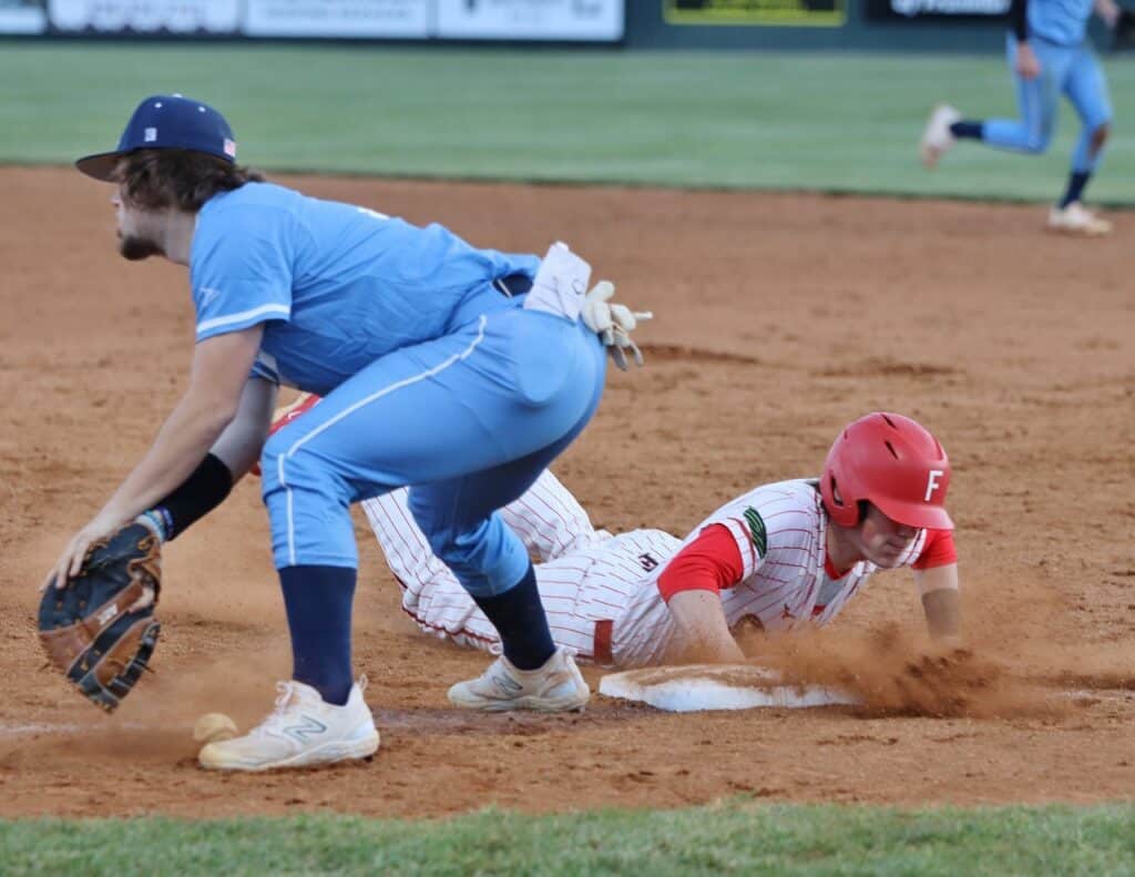Umpire calls safe as player slides into home during undefeated softball streak.