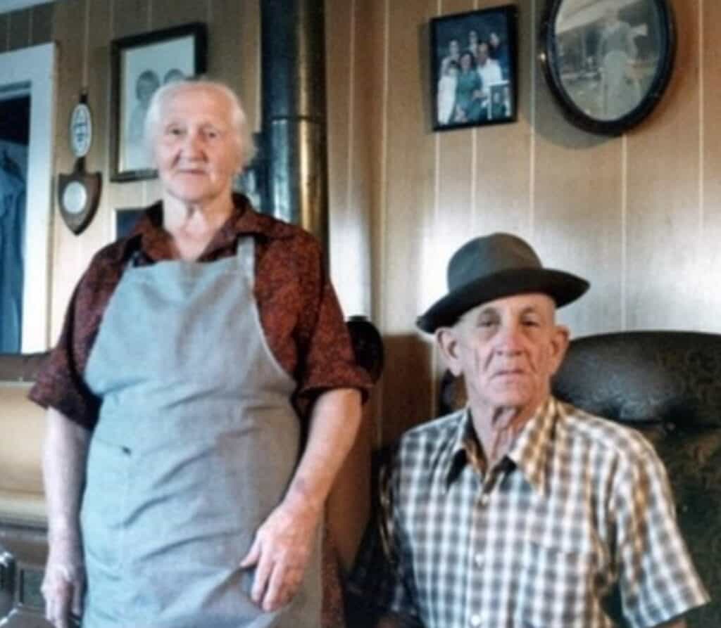 Traditional food preparation with two men working on meat.