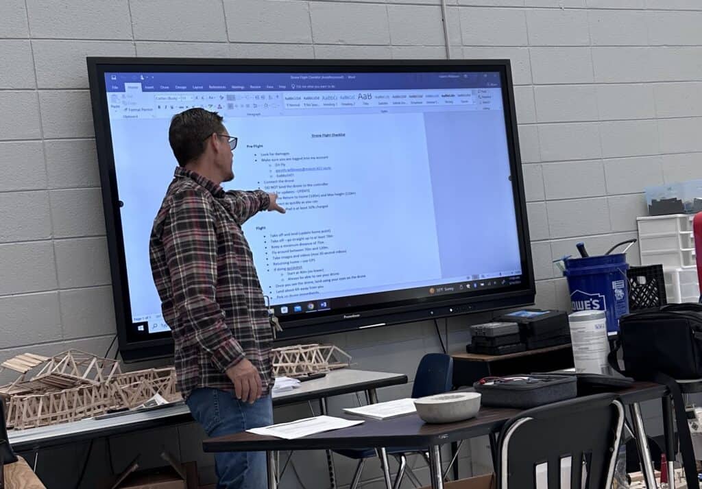 Drone training session with instructor pointing at digital screen.