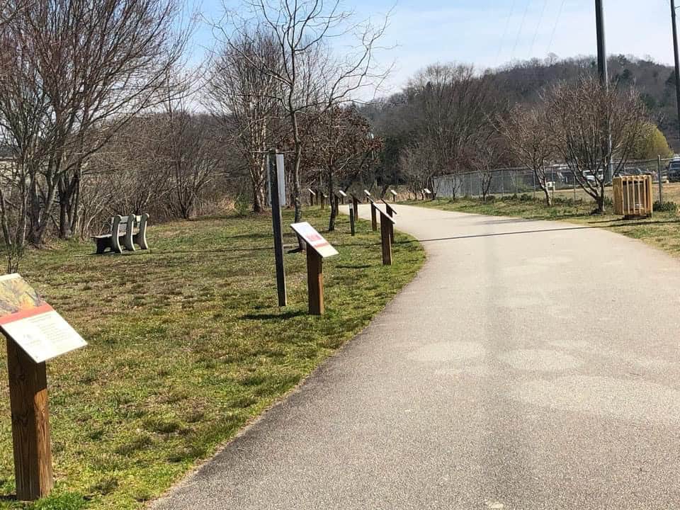 Scenic walking trail at Macon Sense Park with informational signs.