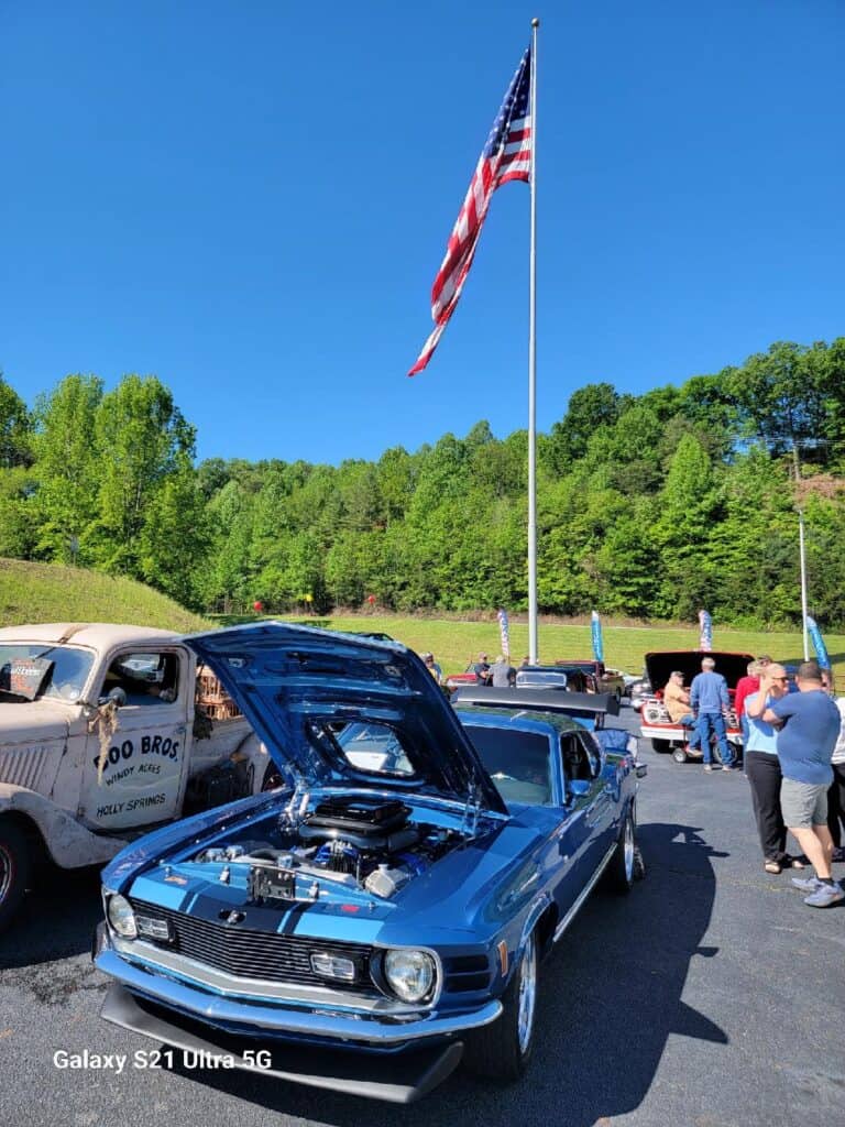 Vintage blue muscle car with open hood at Memorial Day event.