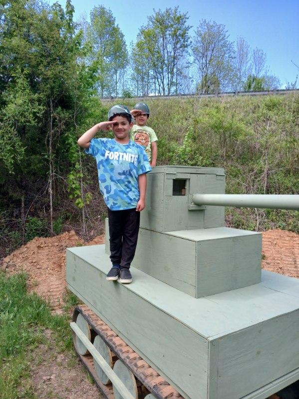 Saluting the flag during Memorial Day at a military tank display.