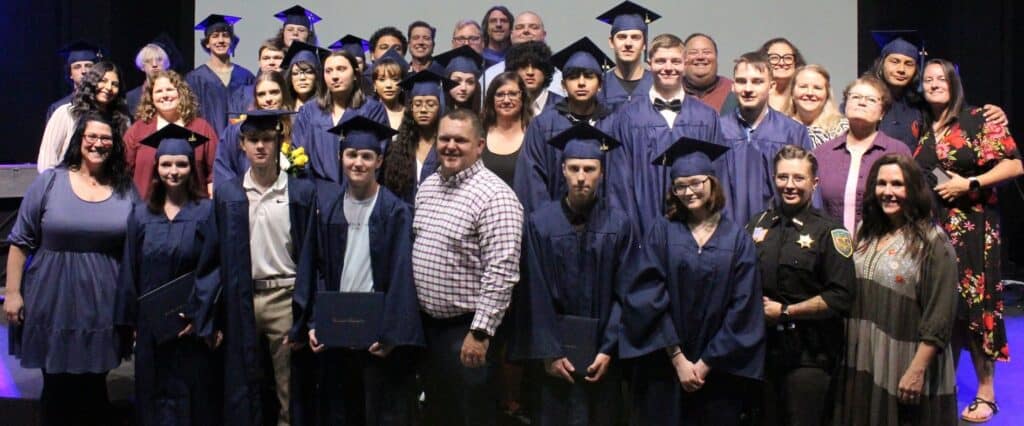 Group of seniors in caps and gowns at Macon County graduation event.