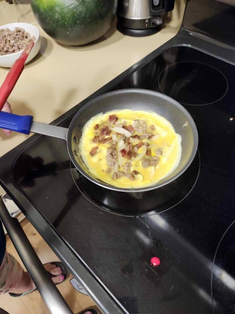 Cooking fresh farm-to-table breakfast eggs with bacon in a skillet.