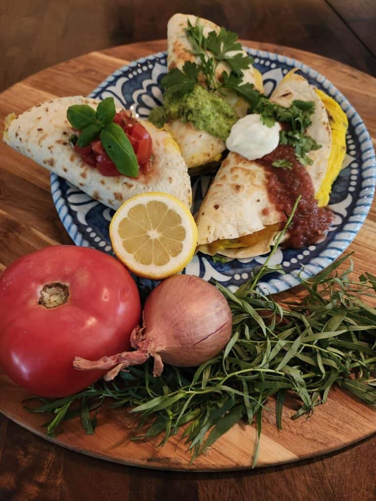 Delicious farm-to-table breakfast with homemade tacos, fresh vegetables, herbs, and lemon slices.
