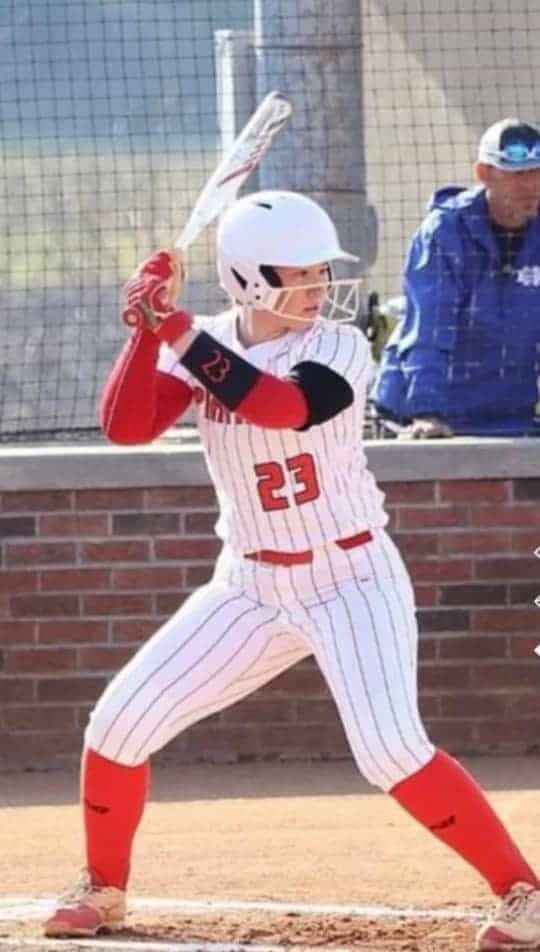 Female softball player in uniform ready to hit during a game.