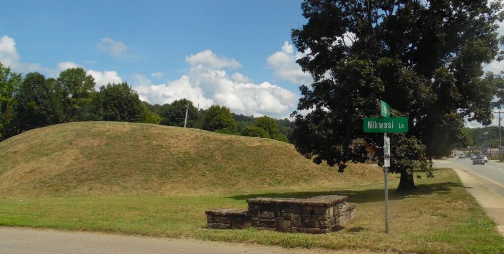 Nikwasi mound with street sign and trees in the background.