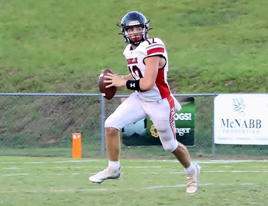Football player in uniform running with the ball on the field.