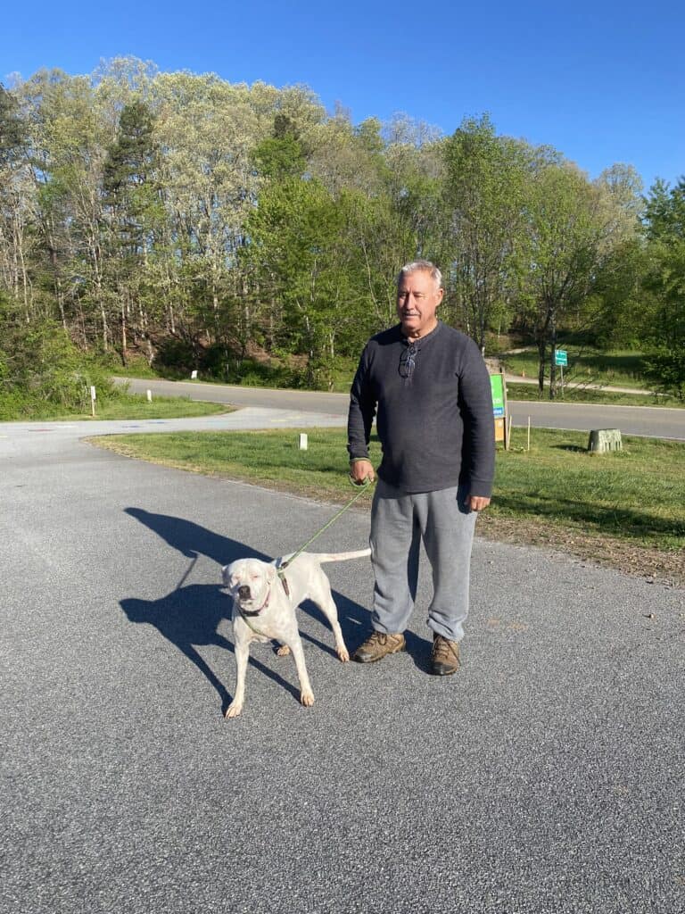 Volunteer walking dog in a park on a sunny day.