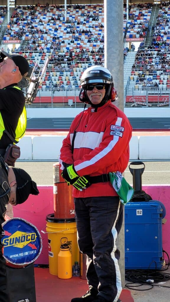 NASCAR firefighter in uniform at racetrack, ready to assist during race events.