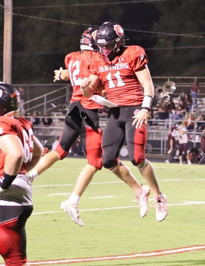 High school football players celebrating on the field during a game.