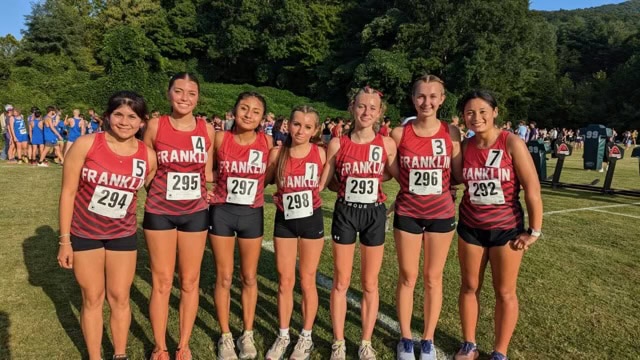 Young female cross country runners in uniform at race start.