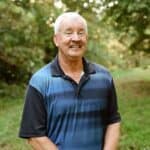 Man smiling outdoors during election season, emphasizing local political engagement.
