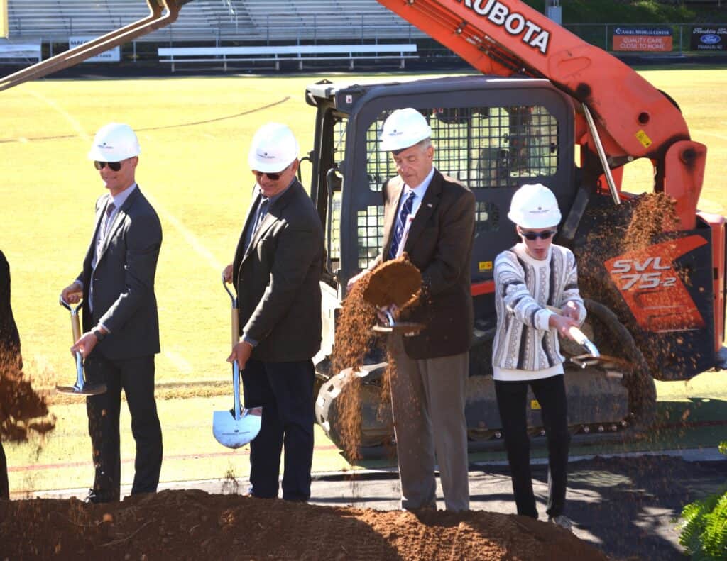Community leaders break ground for new high school in Franklin area with construction equipment.