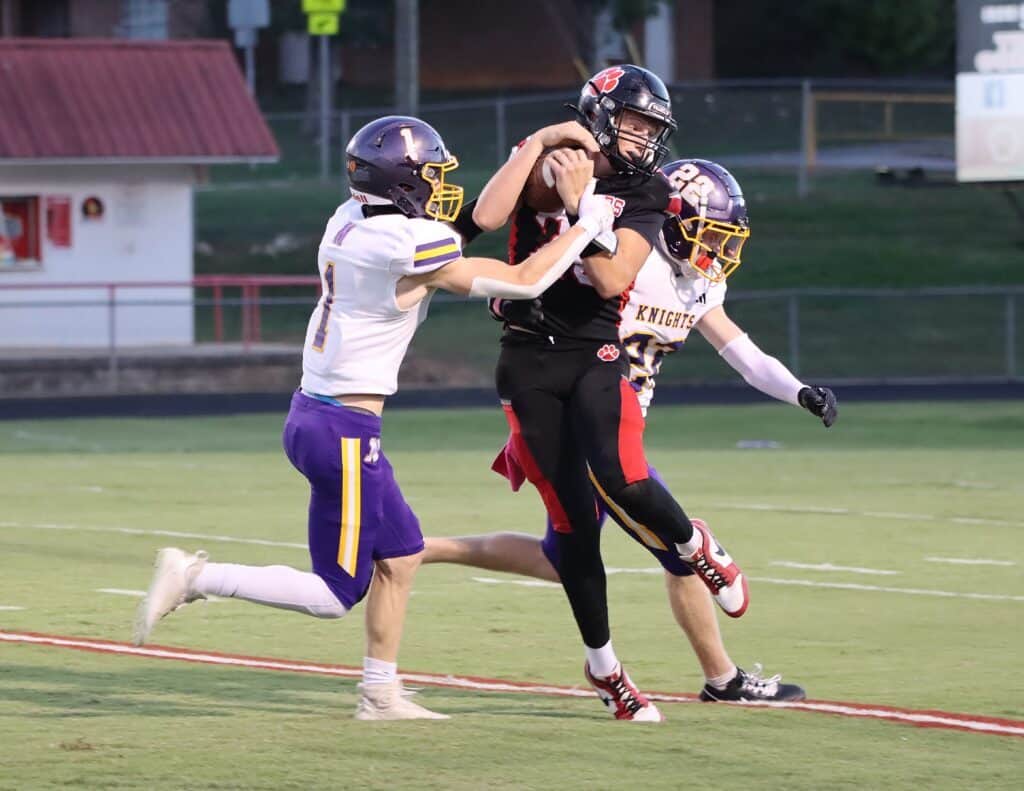 Youth football players in action during a game, with one player holding the ball.
