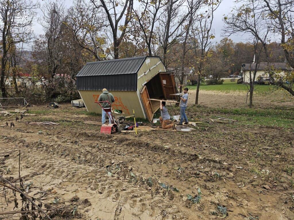 Relocating a small house in a rural area with workers and equipment.