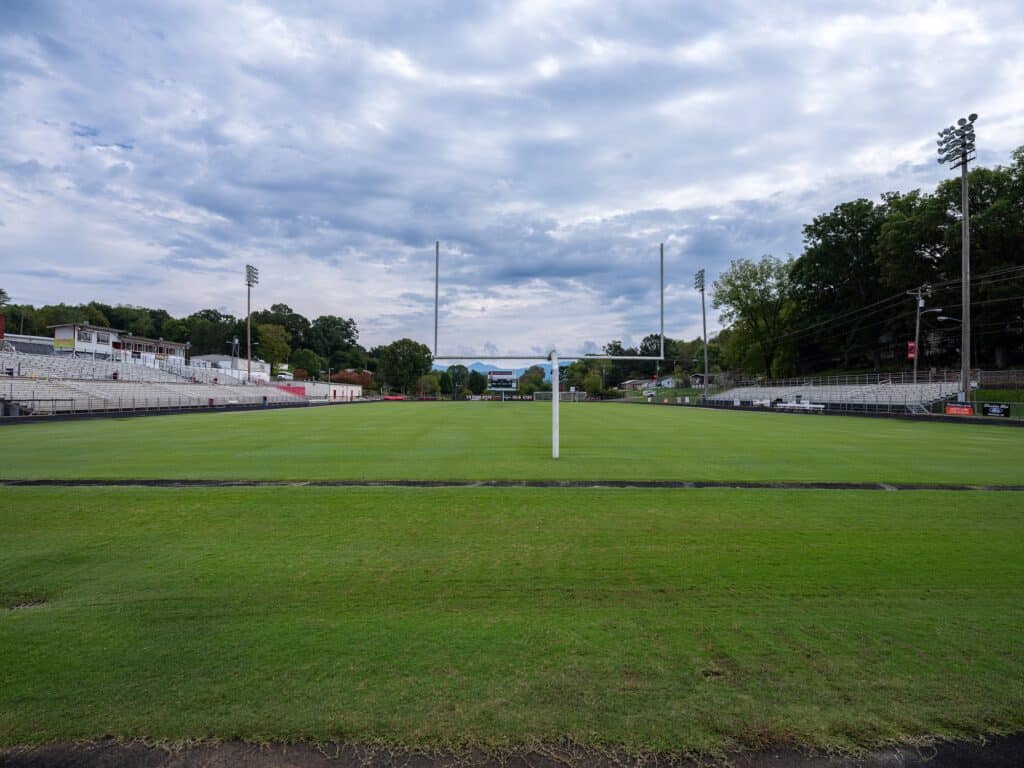 Empty sports stadium field with goalposts and bleachers.