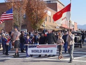 Veterans Day parade in Macon with children, flags, and historical banners.