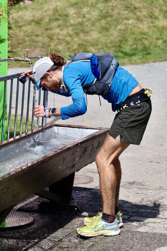 Ultra trail runner drinking water at aid station in France.