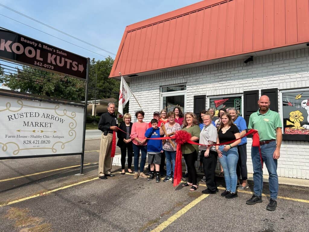Community members celebrate grand opening with ribbon-cutting ceremony outside new business.