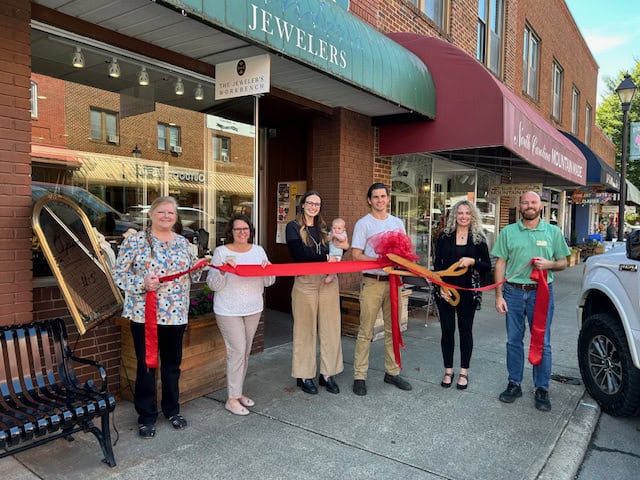 Group of people celebrating grand opening outside jewelry shop.
