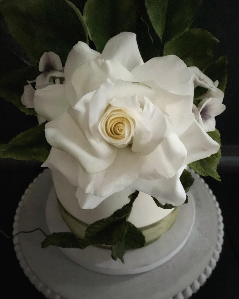 Beautiful white rose cake featuring intricate flower piping techniques for cake decorating enthusias.