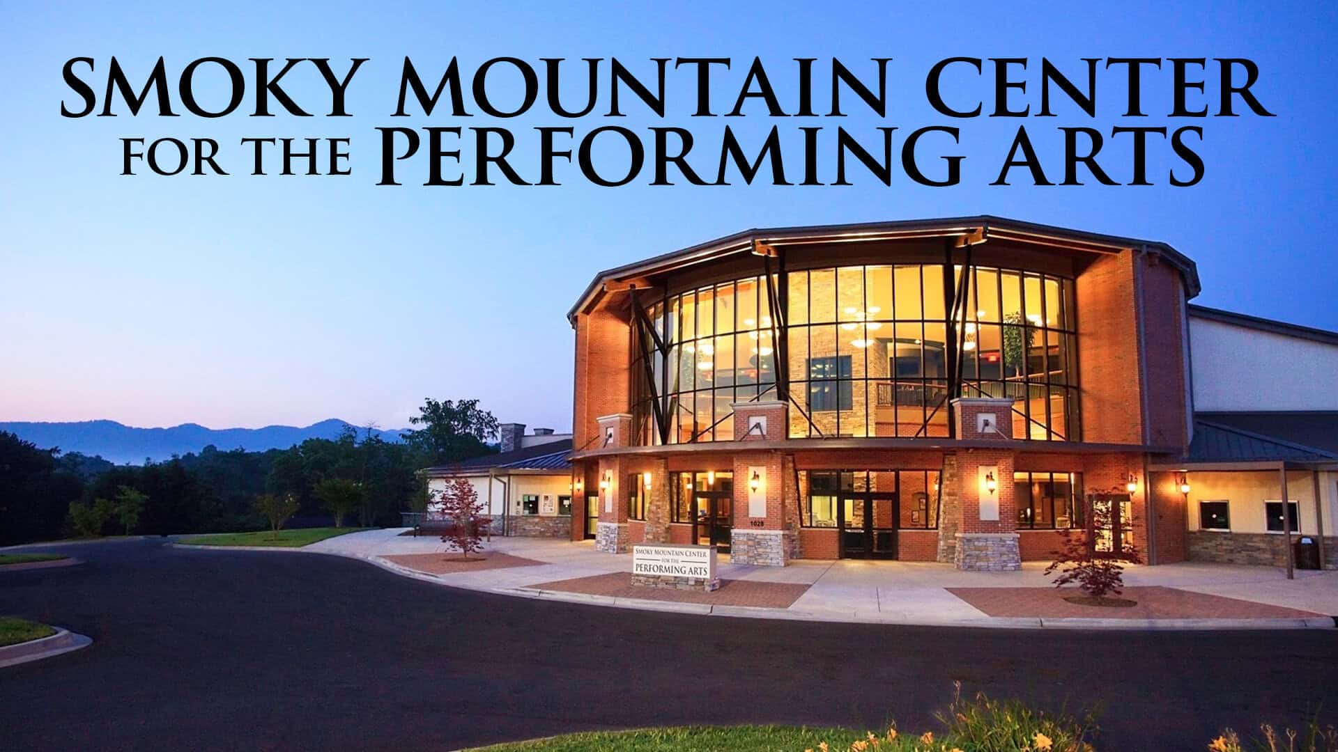 Performing arts center at dusk with modern architecture and glass facade in the Smoky Mountains.