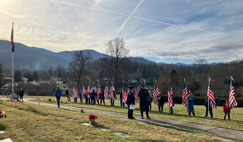 Patriot Guard Riders with American flags honoring veterans outdoors.