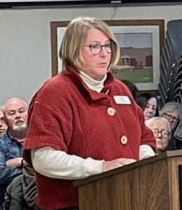 Woman speaking at floodplain management meeting with community members.
