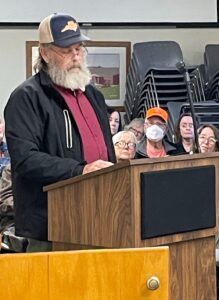 Man speaking at public floodplain management meeting with community members.