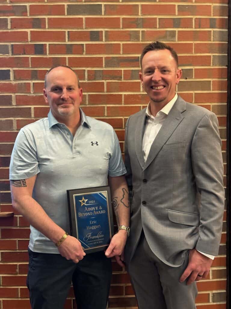 Two men at an award ceremony, one holding a plaque, celebrating local citizens' achievements.