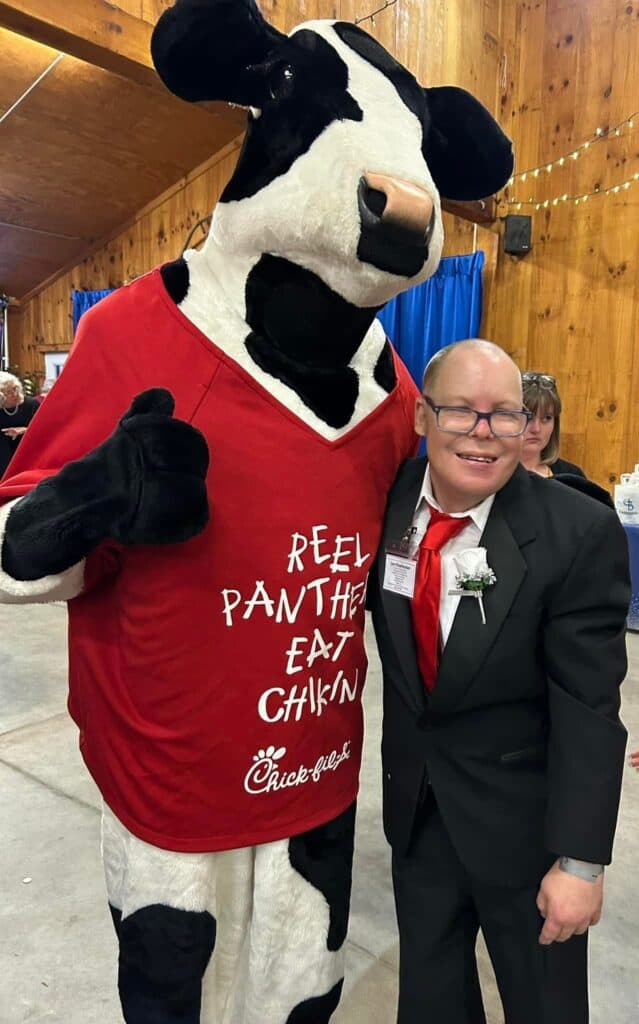 Mascot dressed as a cow with a boy celebrating at Night to Shine event.