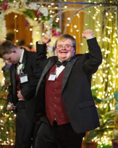 Happy boy celebrating at Night to Shine event with raised fists and joyful expression.